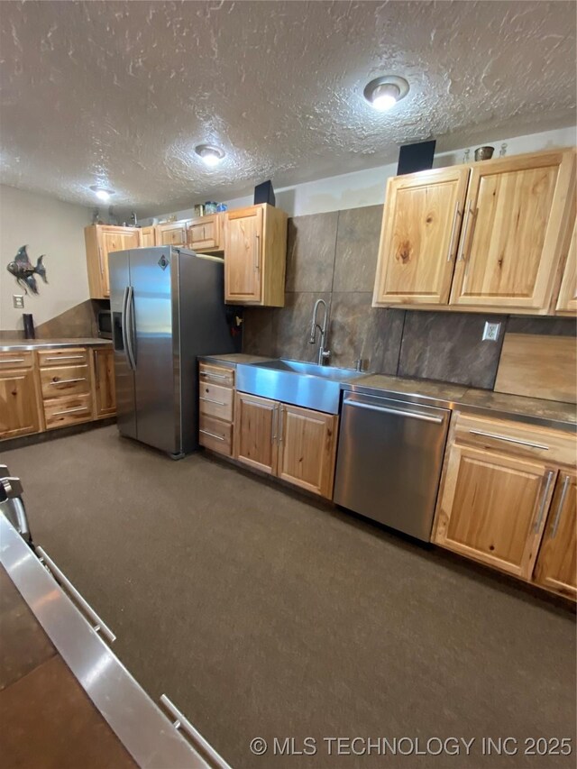 11477 State Highway 70, Madill, OK 73446 - kitchen with appliances with stainless steel finishes, a sink, a textured ceiling, light brown cabinets, and tasteful backsplash