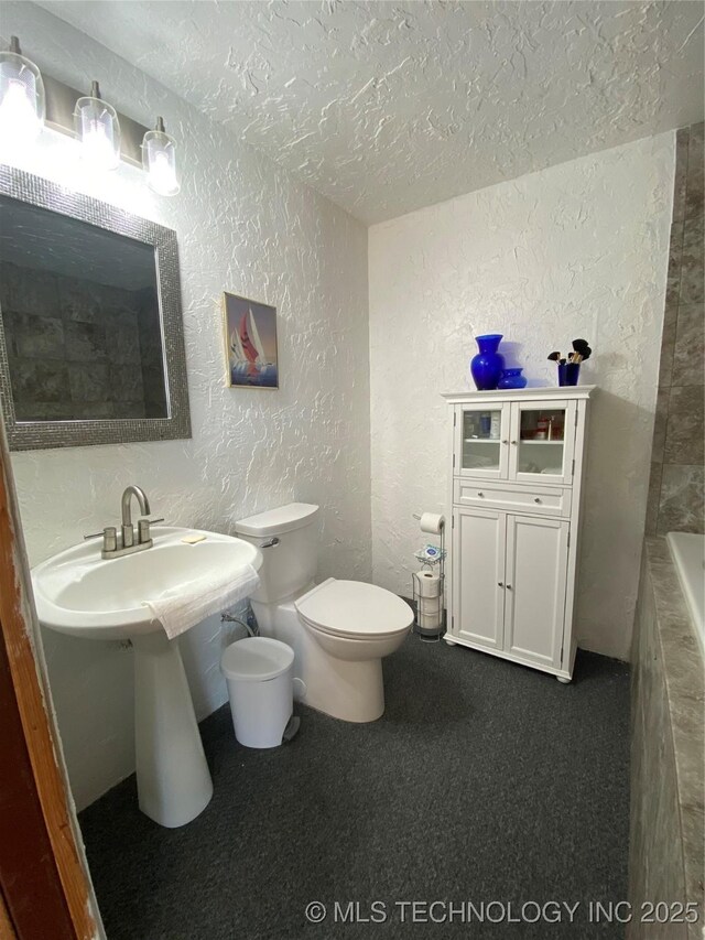 11477 State Highway 70, Madill, OK 73446 - full bathroom with a textured wall, a textured ceiling, toilet, and a tub to relax in