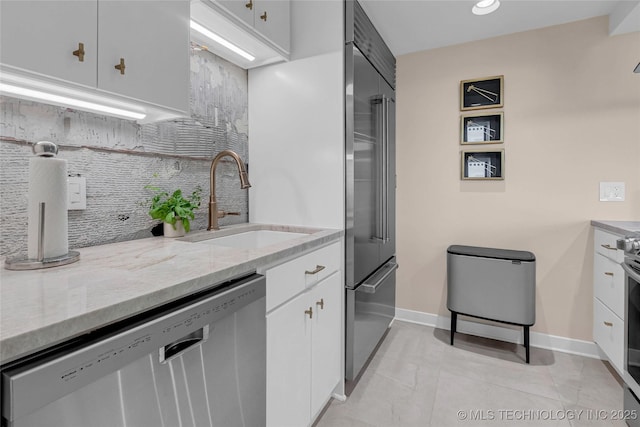 2300 Riverside Dr Unit 7A, Tulsa, OK 74114 - kitchen featuring stainless steel appliances, a sink, backsplash, light stone counters, and white cabinets