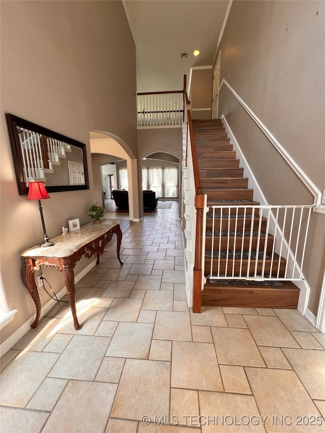 1816 W Sandusky St, Broken Arrow, OK 74012 - stairway featuring arched walkways, stone tile floors, a towering ceiling, and baseboards