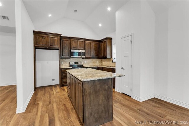 153 Founders Ln, Durant, OK 74701 - kitchen featuring stainless steel appliances, a kitchen island, dark brown cabinets, decorative backsplash, and light wood-style floors