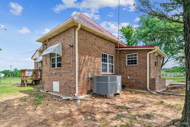 11029 N 3670th Rd, Okemah, OK 74884 - view of side of home featuring cooling unit, brick siding, and metal roof