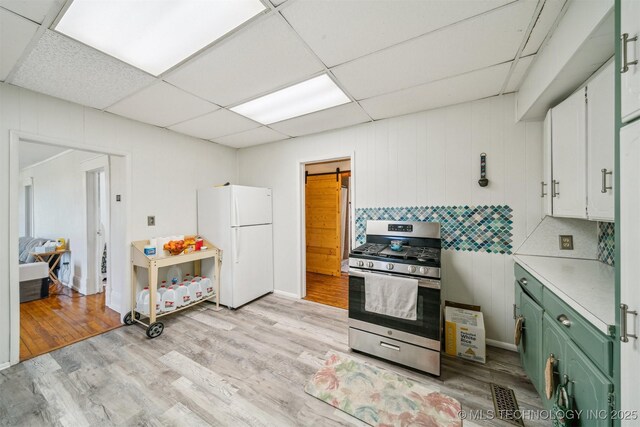 11029 N 3670th Rd, Okemah, OK 74884 - kitchen with stainless steel gas range oven, freestanding refrigerator, green cabinetry, light countertops, and light wood-style floors