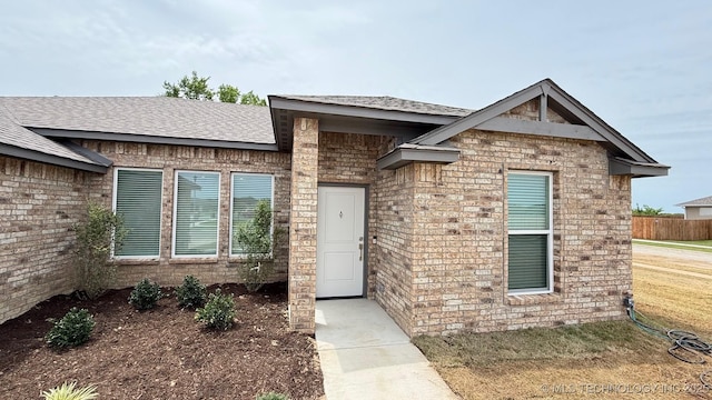 14984 S Oak St, Glenpool, OK 74033 - view of exterior entry featuring roof with shingles, brick siding, and a lawn
