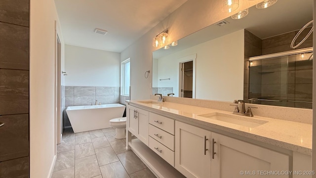 14984 S Oak St, Glenpool, OK 74033 - full bathroom with double vanity, a shower stall, a freestanding bath, tile walls, and toilet