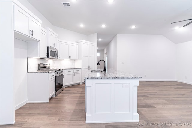 27790 E 109th Pl S, Coweta, OK 74429 - kitchen featuring stainless steel appliances, a sink, a kitchen island with sink, decorative backsplash, and light wood-type flooring