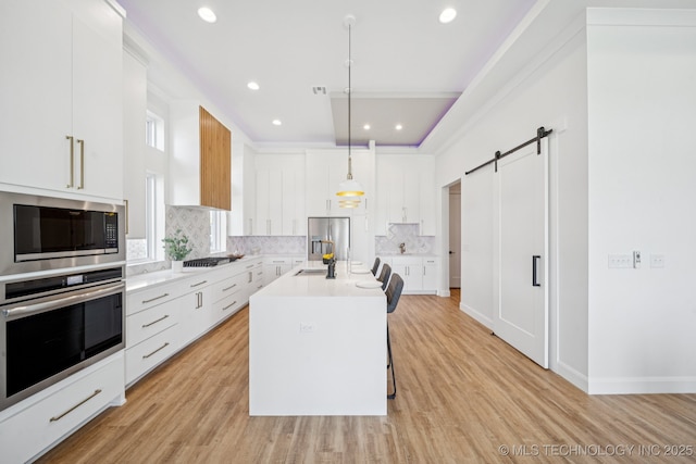2357 E 134th Cir, Bixby, OK 74008 - kitchen featuring appliances with stainless steel finishes, a barn door, tasteful backsplash, light countertops, and white cabinets