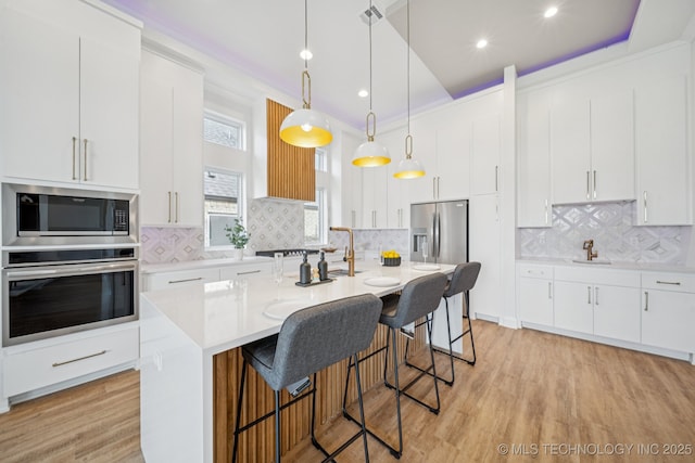 2357 E 134th Cir, Bixby, OK 74008 - kitchen with stainless steel appliances, light countertops, a kitchen bar, backsplash, and recessed lighting