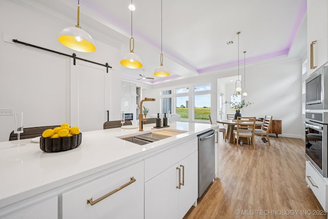 2357 E 134th Cir, Bixby, OK 74008 - kitchen featuring appliances with stainless steel finishes, a barn door, light wood-style flooring, hanging light fixtures, and ornamental molding