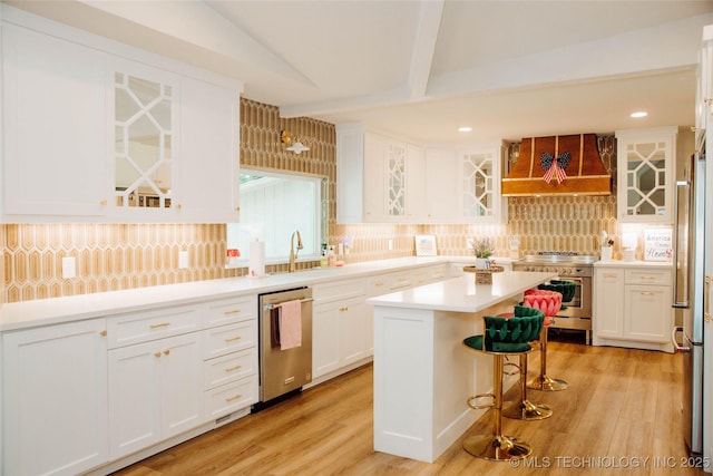 2232 Gershwin Dr, Durant, OK 74701 - kitchen with stainless steel appliances, custom range hood, decorative backsplash, a breakfast bar area, and white cabinetry