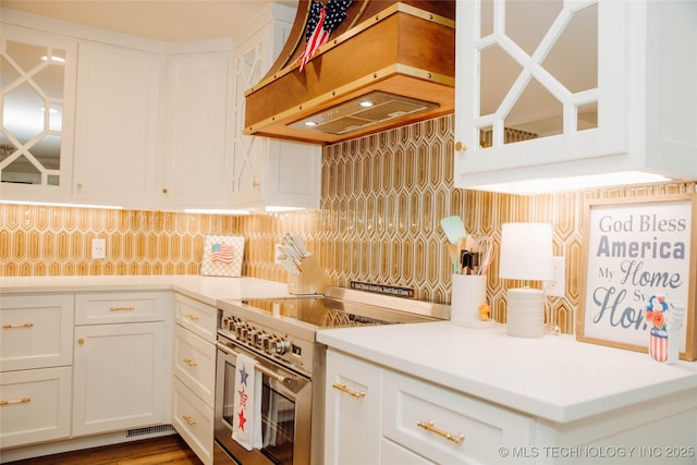 2232 Gershwin Dr, Durant, OK 74701 - kitchen featuring stainless steel range with electric stovetop, custom exhaust hood, white cabinets, decorative backsplash, and glass insert cabinets