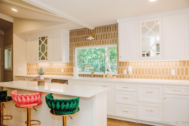 2232 Gershwin Dr, Durant, OK 74701 - kitchen featuring white cabinetry, a breakfast bar, light countertops, a sink, and decorative backsplash