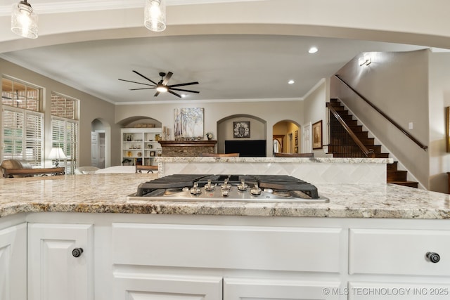 8906 E 110th St, Tulsa, OK 74133 - kitchen with stainless steel gas cooktop, arched walkways, a ceiling fan, white cabinetry, and ornamental molding