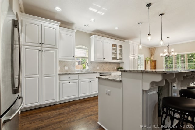 8906 E 110th St, Tulsa, OK 74133 - kitchen featuring freestanding refrigerator, a kitchen breakfast bar, crown molding, tasteful backsplash, and white cabinetry