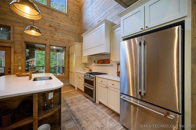 475 Bear Pine Trl, Broken Bow, OK 74728 - kitchen featuring high end appliances, wood walls, light countertops, a towering ceiling, and custom range hood