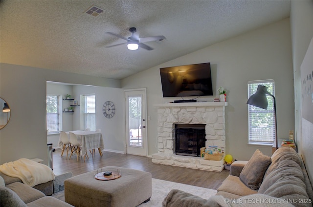 13866 S Nyssa Pl, Glenpool, OK 74033 - living area with vaulted ceiling, a textured ceiling, wood finished floors, a stone fireplace, and a ceiling fan