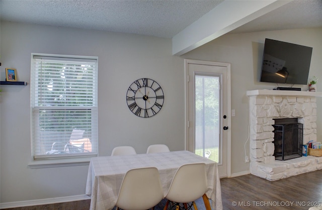 13866 S Nyssa Pl, Glenpool, OK 74033 - dining area with wood finished floors, a stone fireplace, a textured ceiling, and baseboards