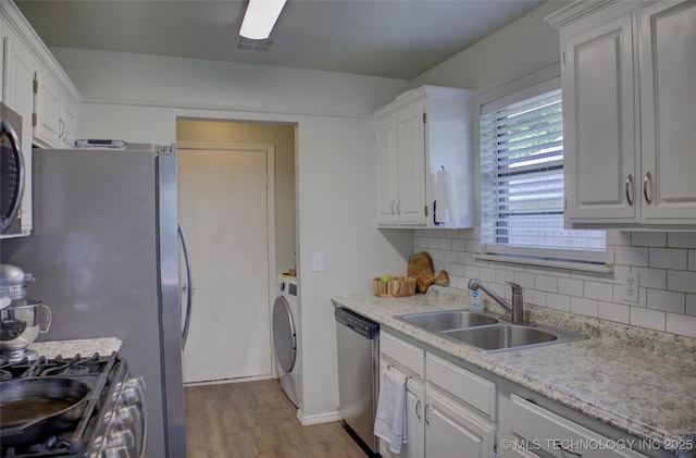 13866 S Nyssa Pl, Glenpool, OK 74033 - kitchen featuring stainless steel appliances, a sink, washer / clothes dryer, wood finished floors, and backsplash