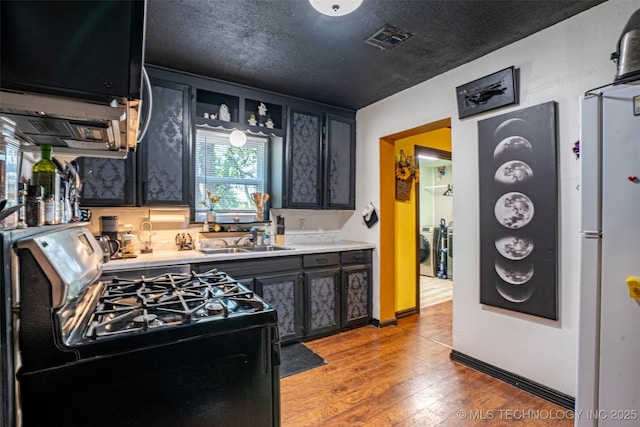 420 E Elm St, Skiatook, OK 74070 - kitchen with range with gas cooktop, dark cabinets, a sink, light countertops, and washer / clothes dryer