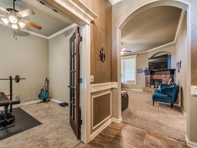 18210 E 49th St, Tulsa, OK 74134 - workout room featuring a ceiling fan, arched walkways, carpet flooring, crown molding, and a brick fireplace
