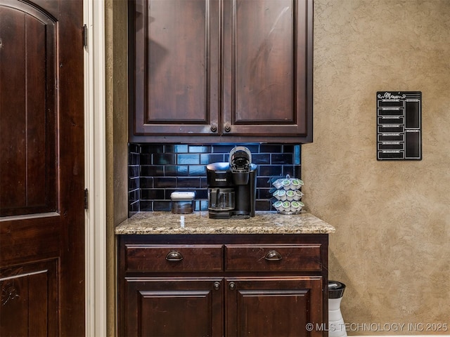 18210 E 49th St, Tulsa, OK 74134 - kitchen featuring dark brown cabinetry, backsplash, light stone counters, and a textured wall
