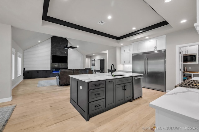 5769 S 256th E Ave, Broken Arrow, OK 74014 - kitchen featuring built in appliances, a sink, white cabinetry, a raised ceiling, and light wood-style flooring