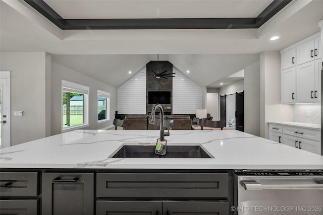 5769 S 256th E Ave, Broken Arrow, OK 74014 - kitchen featuring a sink, open floor plan, dishwasher, light stone counters, and white cabinetry