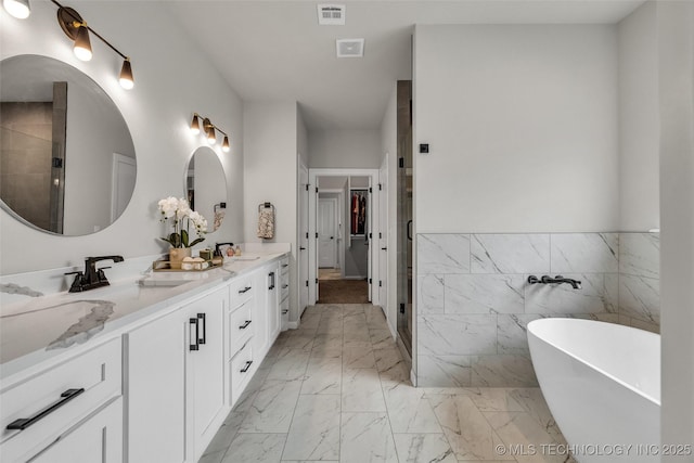5769 S 256th E Ave, Broken Arrow, OK 74014 - bathroom featuring double vanity, a freestanding bath, marble finish flooring, a stall shower, and tile walls
