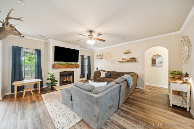 2704 W Imperial St, Broken Arrow, OK 74011 - living room featuring ceiling fan, arched walkways, wood finished floors, a fireplace, and baseboards