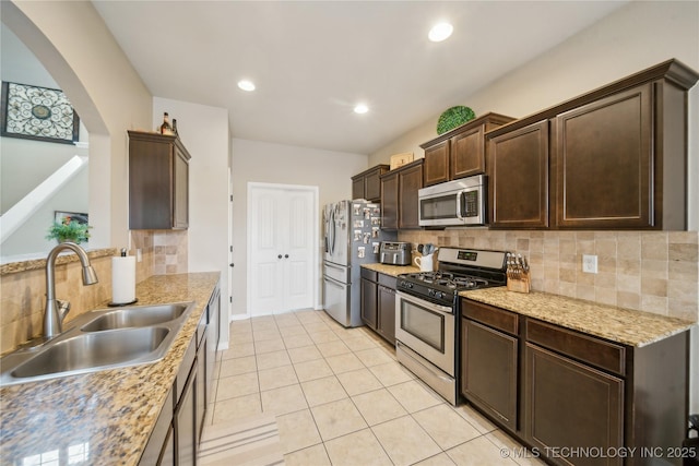 2704 W Imperial St, Broken Arrow, OK 74011 - kitchen with stainless steel appliances, a sink, arched walkways, dark brown cabinetry, and backsplash