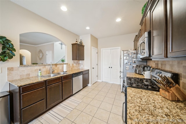2704 W Imperial St, Broken Arrow, OK 74011 - kitchen with appliances with stainless steel finishes, a sink, backsplash, dark brown cabinetry, and arched walkways