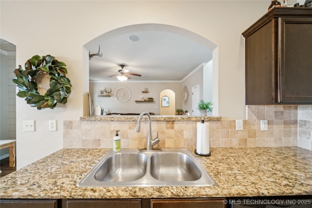 2704 W Imperial St, Broken Arrow, OK 74011 - kitchen with a sink, a ceiling fan, dark brown cabinets, arched walkways, and crown molding