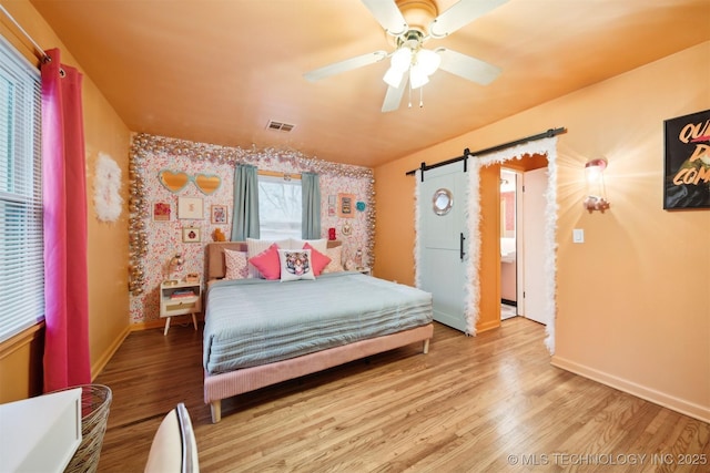 1610 S Ash Ave, Broken Arrow, OK 74012 - bedroom with a barn door, baseboards, wood finished floors, wallpapered walls, and ceiling fan