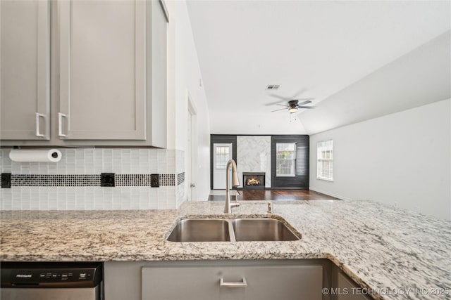 10901 E 95th St N, Owasso, OK 74055 - kitchen with stainless steel dishwasher, a sink, a ceiling fan, light stone countertops, and a fireplace
