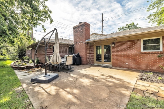 4023 E 36th St S, Tulsa, OK 74135 - rear view of house featuring brick siding, a patio area, a chimney, and roof with shingles