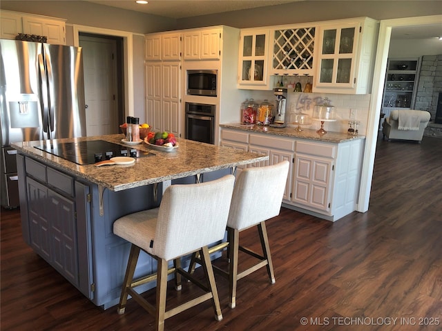 18820 Ridge Rd, Catoosa, OK 74015 - kitchen with appliances with stainless steel finishes, dark wood-style floors, a center island, white cabinetry, and recessed lighting