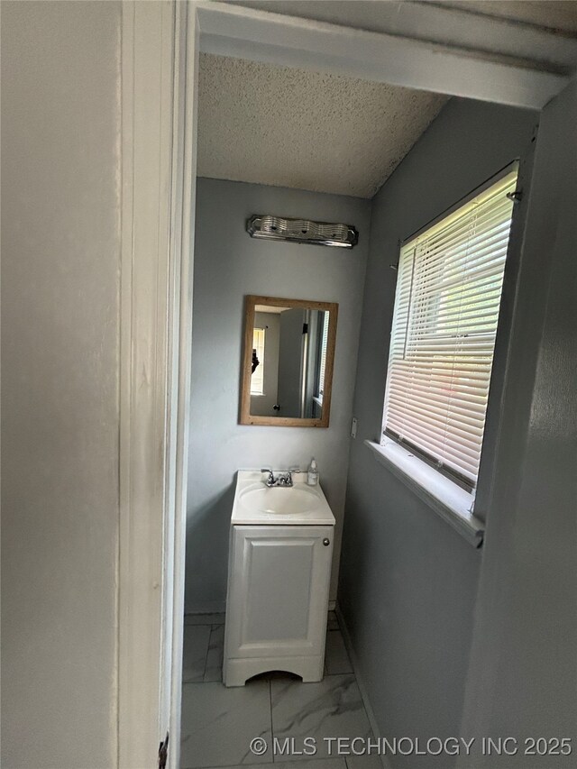 1310 S 38th St, Muskogee, OK 74401 - bathroom with marble finish floors, vanity, and a textured ceiling