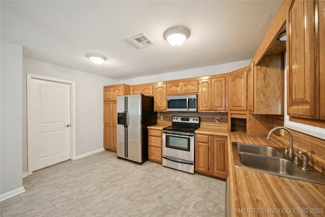 1703 Elm St, Owasso, OK 74055 - kitchen featuring stainless steel appliances, a sink, and brown cabinets