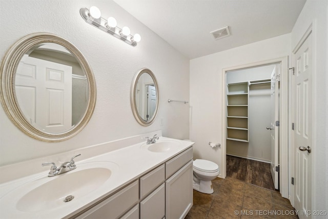 bathroom featuring double vanity, tile patterned flooring, and a walk in closet
