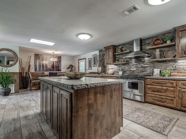 32188 E 738th Rd, Wagoner, OK 74467 - kitchen with open shelves, stainless steel gas stove, wall chimney exhaust hood, tasteful backsplash, and a kitchen island