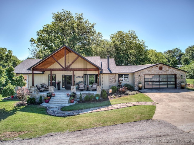 32188 E 738th Rd, Wagoner, OK 74467 - view of front of home with stone siding, concrete driveway, a front yard, a garage, and a porch