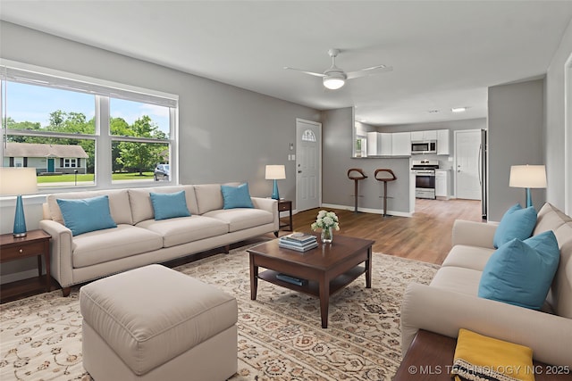 245 E 148th St S, Glenpool, OK 74033 - living room featuring light wood-style flooring, a ceiling fan, and baseboards