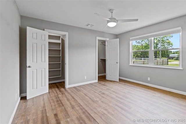 245 E 148th St S, Glenpool, OK 74033 - unfurnished bedroom with a walk in closet, wood finished floors, baseboards, and ceiling fan