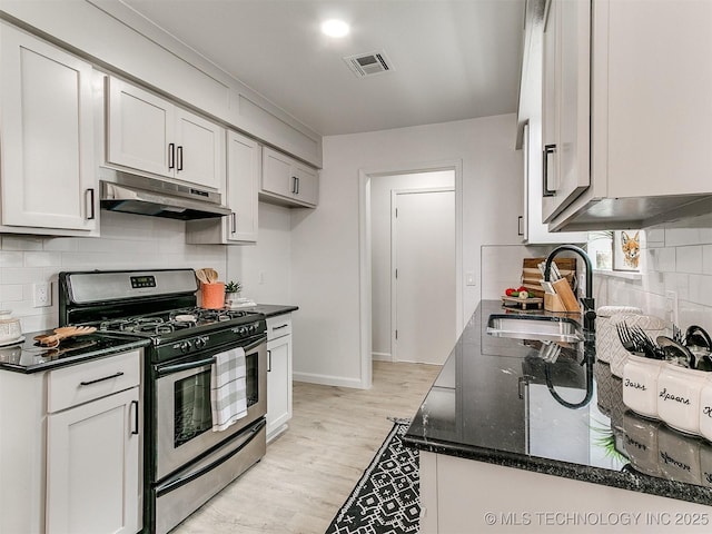 316 E Austin St, Broken Arrow, OK 74011 - kitchen featuring stainless steel range with gas stovetop, under cabinet range hood, a sink, backsplash, and dark stone countertops