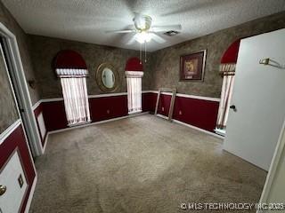 1408 11th NW, Ardmore, OK 73401 - unfurnished room with a textured ceiling, ceiling fan, carpet, a wainscoted wall, and wallpapered walls