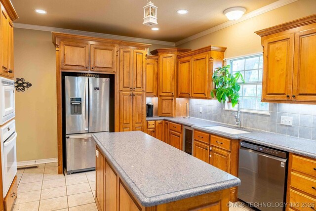 210 S Water St, Sapulpa, OK 74066 - kitchen with stainless steel appliances, a sink, tasteful backsplash, brown cabinetry, and a kitchen island