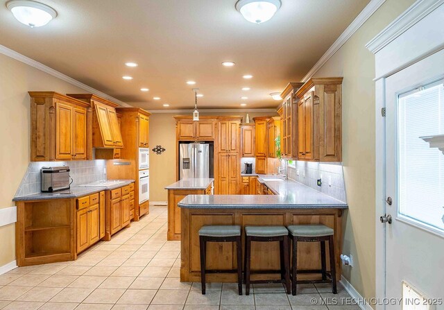 210 S Water St, Sapulpa, OK 74066 - kitchen with white appliances, a peninsula, decorative backsplash, brown cabinetry, and crown molding