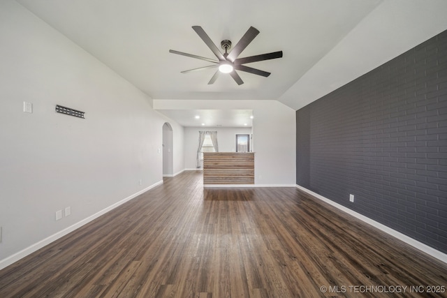5976 E 147th St S, Bixby, OK 74008 - unfurnished living room featuring arched walkways, ceiling fan, dark wood finished floors, brick wall, and baseboards