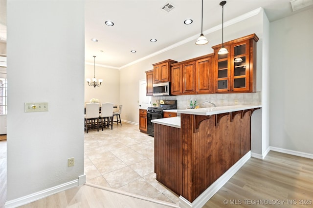 4701 S 179th E Ave, Tulsa, OK 74134 - kitchen featuring gas stove, stainless steel microwave, a breakfast bar, light countertops, and ornamental molding