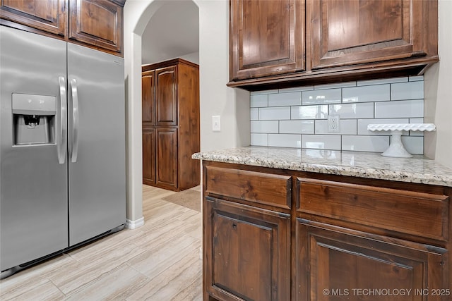 12441 S 209th W Ave, Sapulpa, OK 74066 - kitchen featuring stainless steel fridge, arched walkways, backsplash, light wood-style floors, and light stone countertops